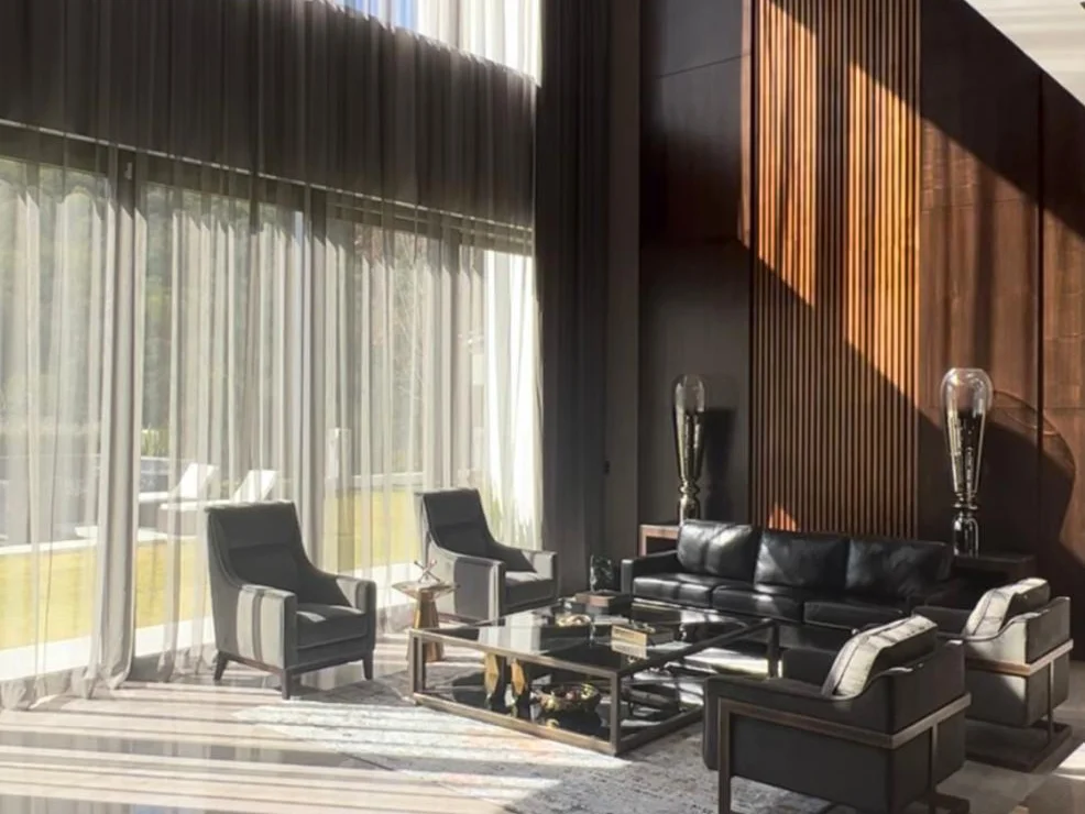 Ambiente de sala elegante donde destacan las cortinas de tela tras los sillones