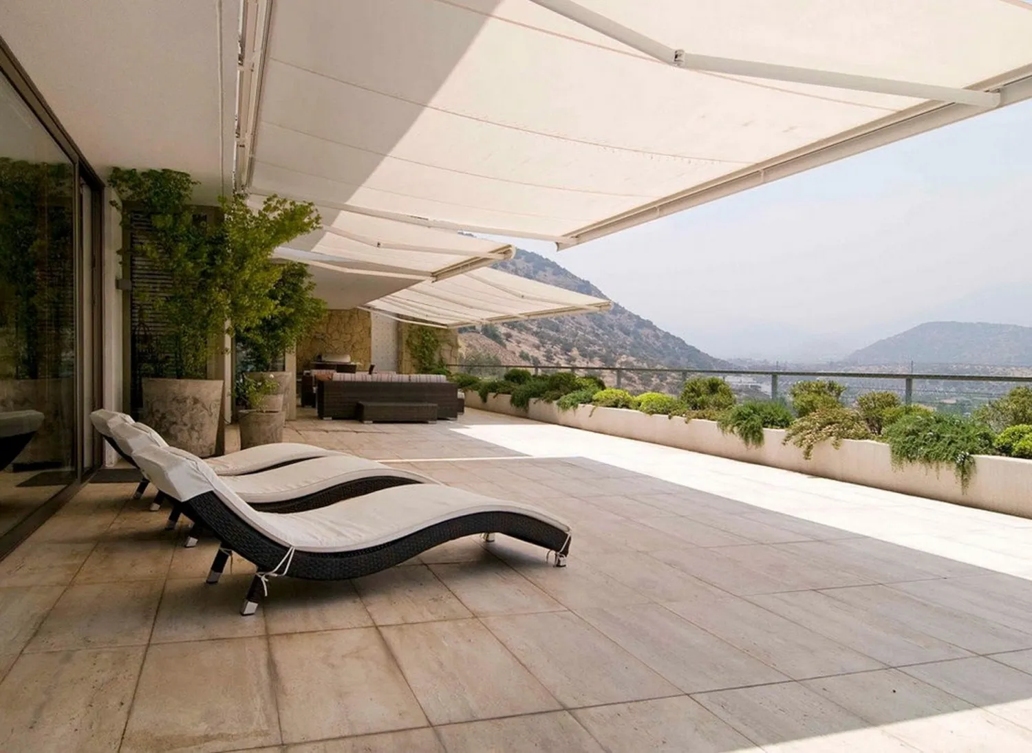 Toldo vertical instalado en un área exterior, con sillones modernos para crear un ambiente cómodo y elegante al aire libre.